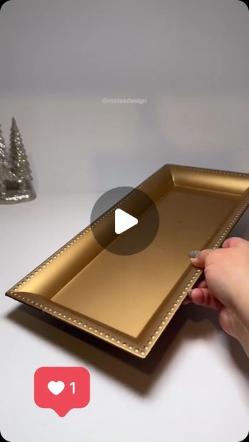 a person is holding a gold tray on a table