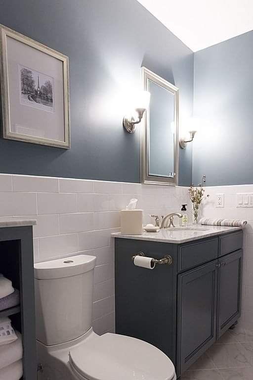 a white toilet sitting next to a sink in a bathroom under two framed pictures on the wall