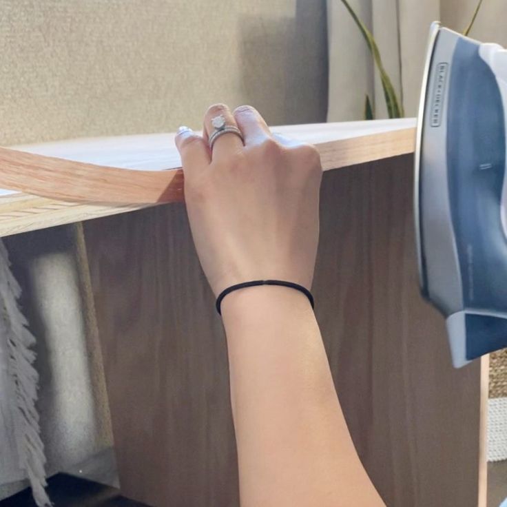 a woman is using an iron on a piece of wood to make a cabinet top