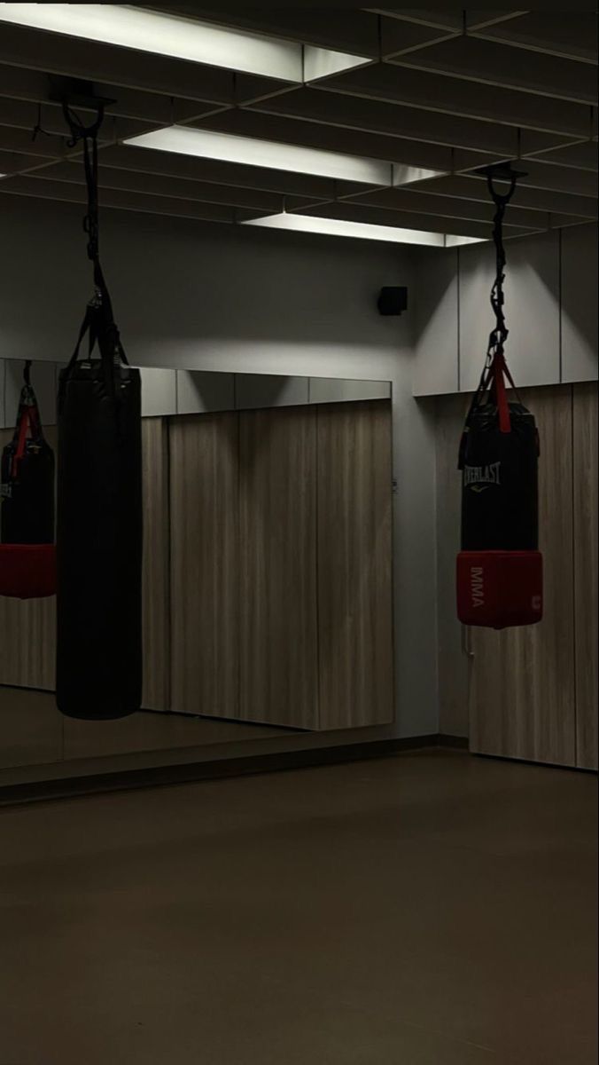 an empty gym with boxing gloves hanging from the ceiling and punching bags on the wall