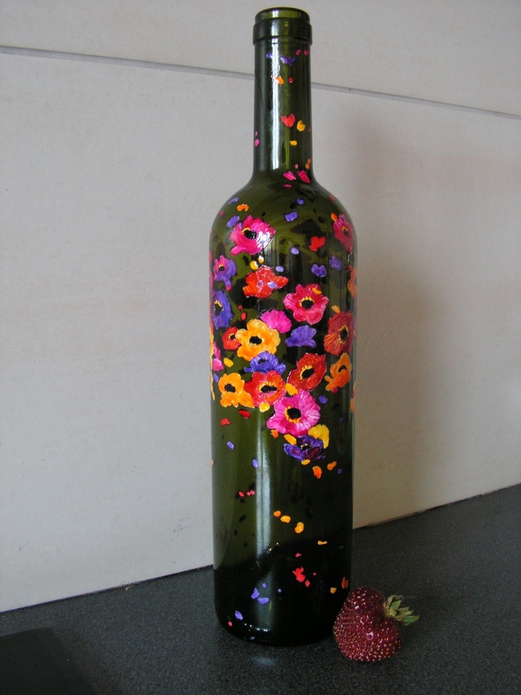 a bottle with flowers painted on it next to a strawberry