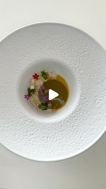 a white plate with some food in it and a small bowl on the side that is filled with olive oil