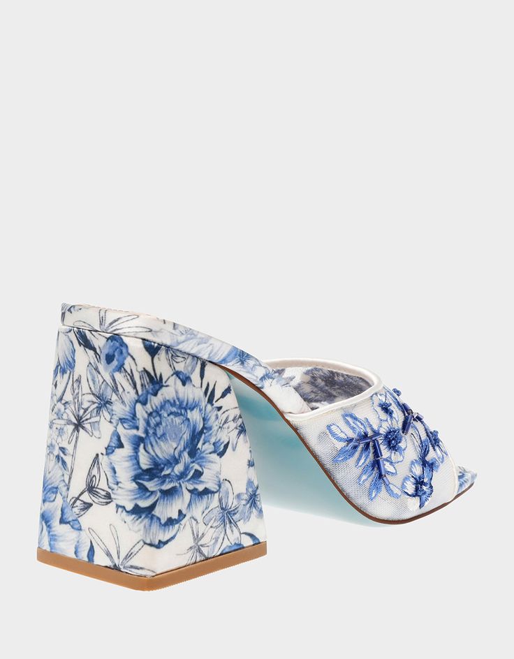 Transform from day to night with the ROO Blue Floral slip-on heel! This stunning sandal features a sturdy block heel and a breezy slip-on toe strap embellished with vibrant blue floral patterns, making it the perfect match for dresses or denim. Mesh textile upper material with beaded embellishments Synthetic lining/sock Synthetic Betsey Blue sole 3.75 inch heel height Imported Summer Block Heels With Removable Insole And Pointed Toe, Spring Slip-on Heels With Heel Strap, Spring Wooden Heel Slip-on Heels, Spring Slip-on Heels With Wooden Heel, Blue Spring Mules With Wooden Heel, Spring Blue Block Heels With Heel Strap, Blue Sandals With Wooden Heel For Spring, Blue Block Heels With Padded Heel For Spring, Blue Padded Heel Block Heels For Spring