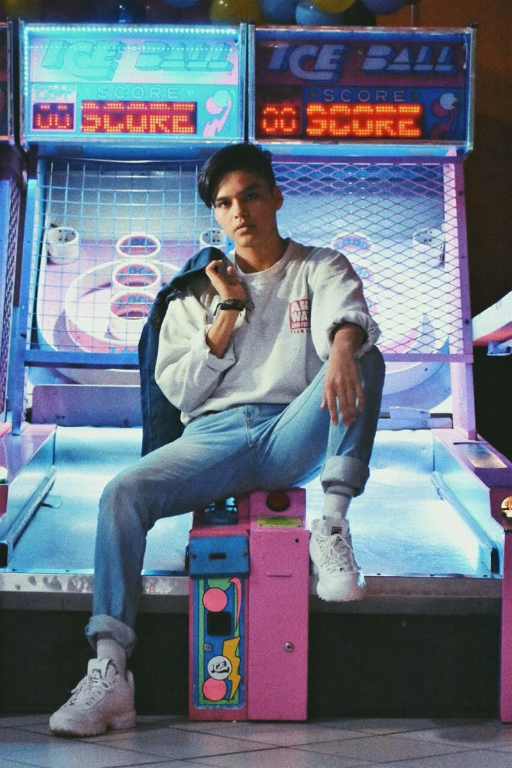 a young man sitting on top of a pink table next to a machine hockey game