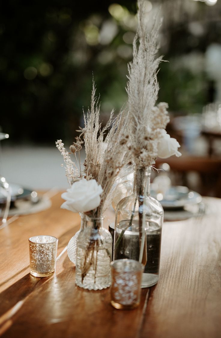 there are two vases with flowers in them sitting on the dining room table at this wedding reception