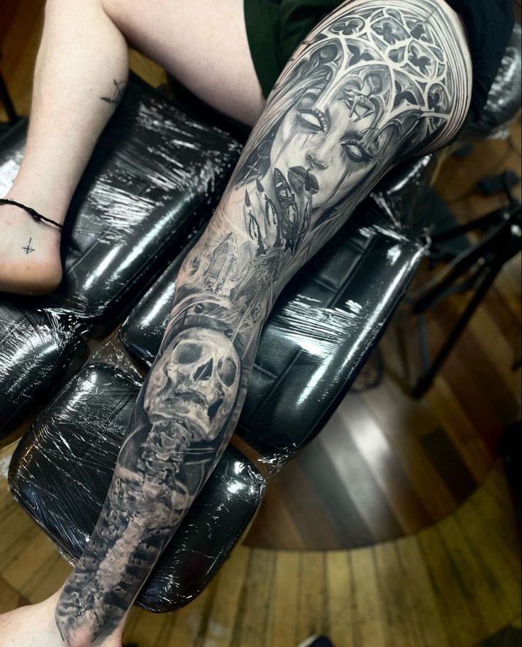 a person with tattoos on their legs sitting in a chair