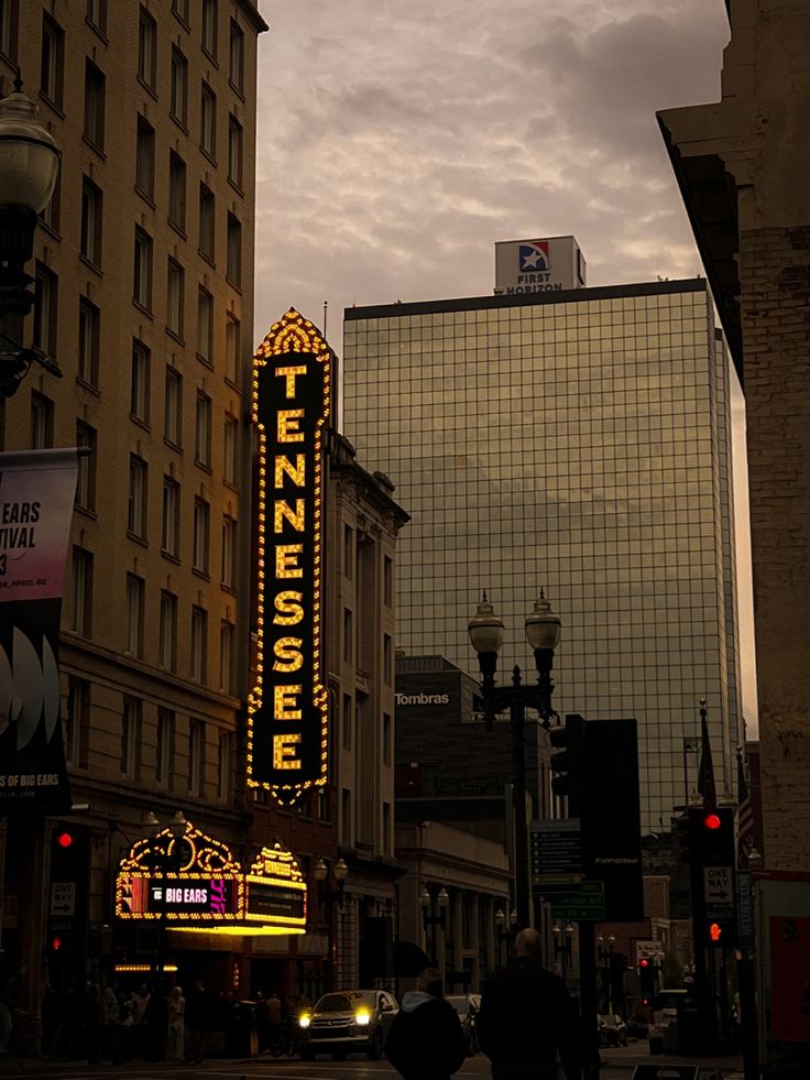 the neon sign for tennessense is lit up in front of some tall buildings