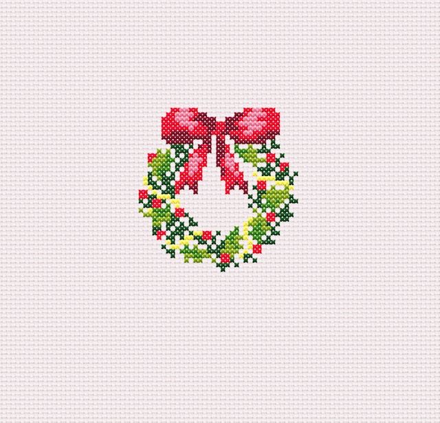 a cross stitched christmas wreath with red bows on it's front and side