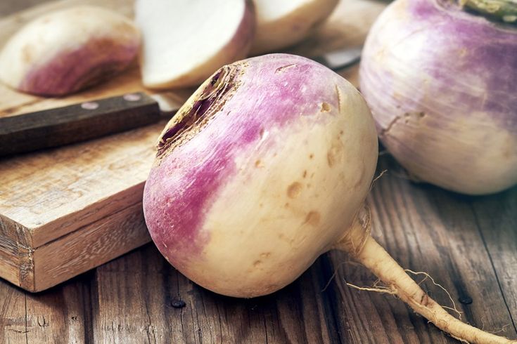 an onion sitting on top of a wooden cutting board next to some onions and a knife