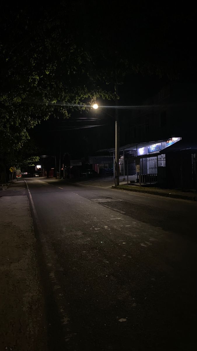 an empty street at night with the light on and no one in it or someone out