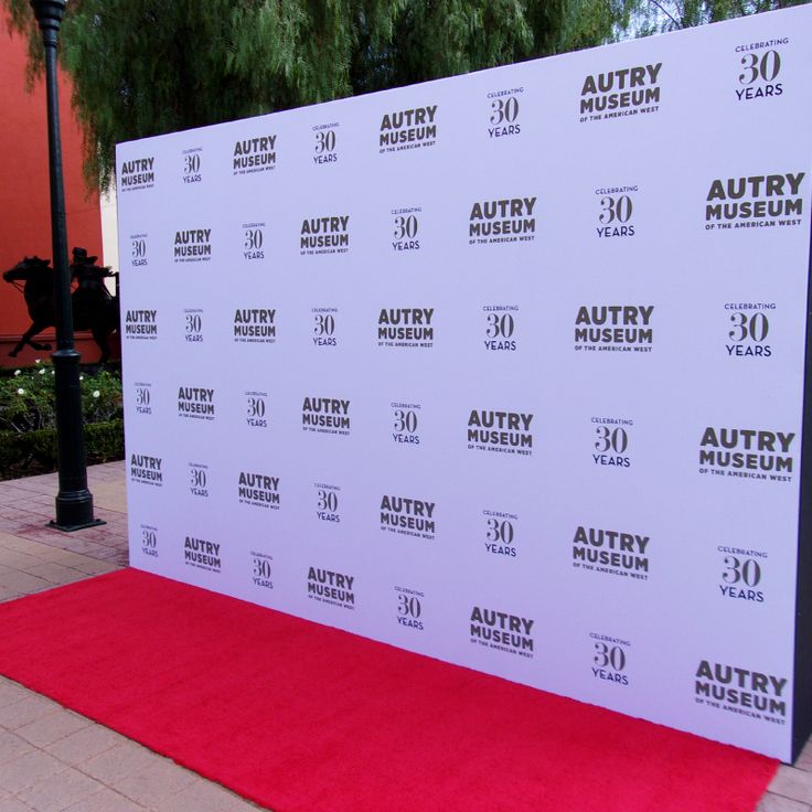 a red carpet is on the ground in front of a white wall with an advertisement