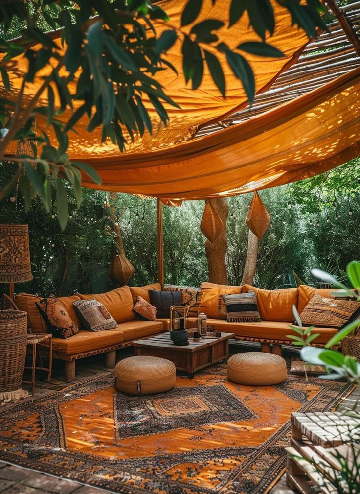 an outdoor living area with orange couches and rugs on the floor, surrounded by greenery