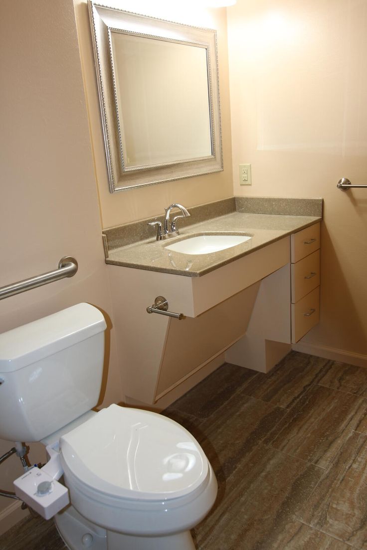 a white toilet sitting next to a sink in a bathroom under a mirror above it