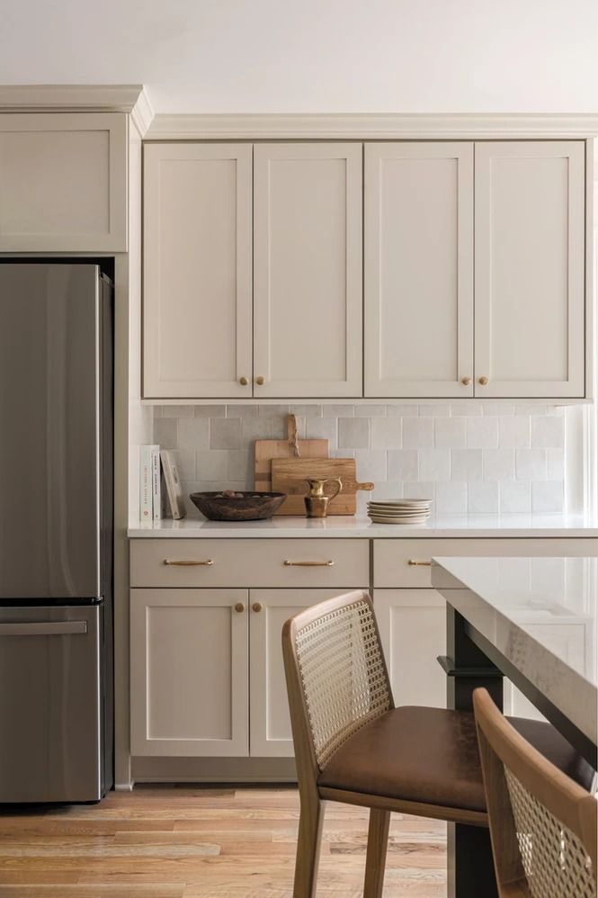 a kitchen with white cabinets and stainless steel appliances, including a silver refrigerator freezer