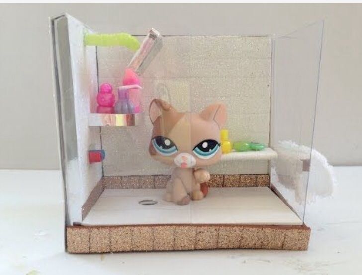 a small toy cat sitting inside of a glass case on top of a white table