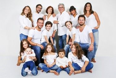 a large group of people posing for a family photo with one child and two adults