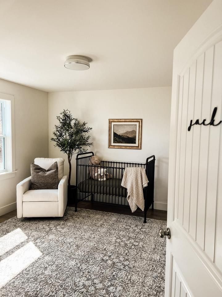 a baby crib in the corner of a room with a chair and rug on the floor