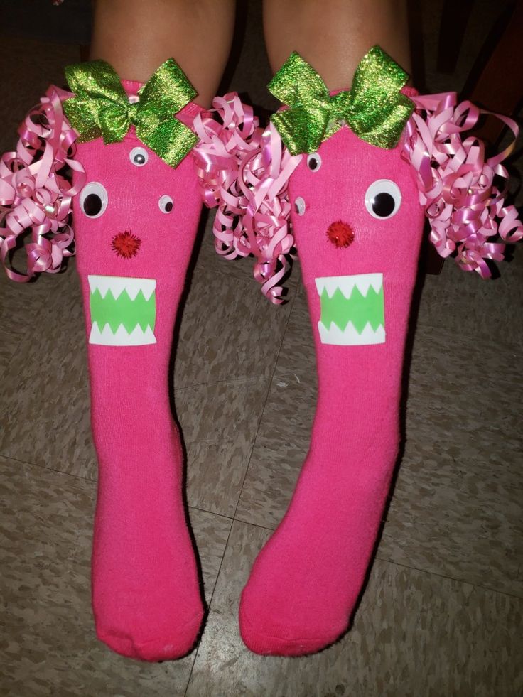 pair of pink socks with green bows and flowers on them, decorated to look like carrots