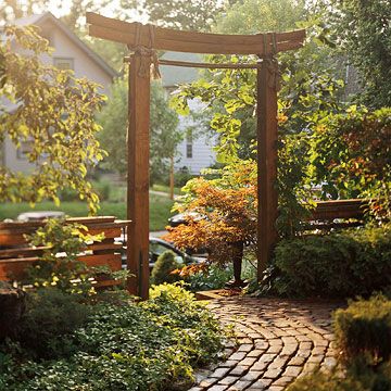 a brick pathway leading to a wooden arbor