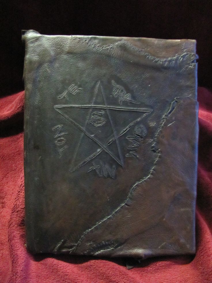 an old book sitting on top of a red cloth covered tablecloth with writing and symbols