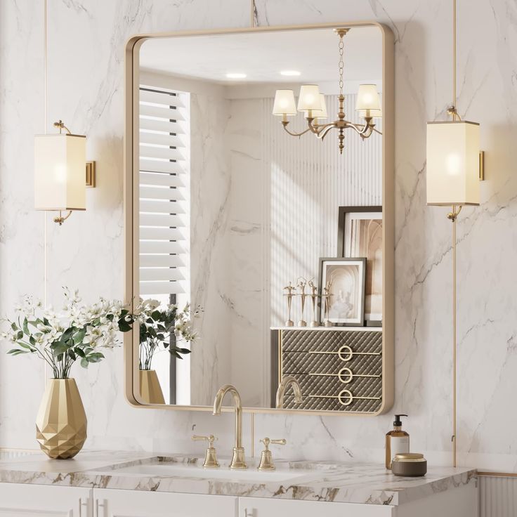 a bathroom with marble counter tops and gold accents on the mirror above it is a vase filled with flowers