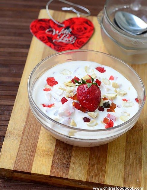 a bowl of yogurt with strawberries and nuts in it on a cutting board