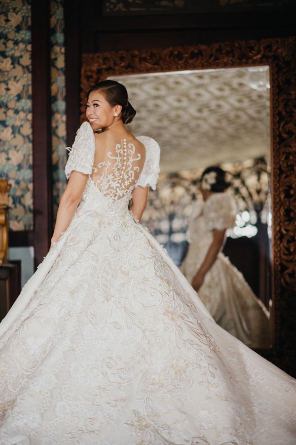 a woman standing in front of a mirror wearing a wedding dress