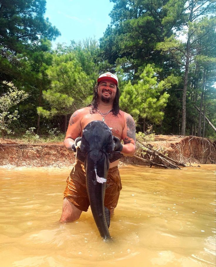 a man in the water with an animal on his back and trees in the background