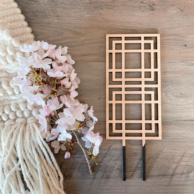 a pair of scissors sitting on top of a wooden cutting board next to some flowers