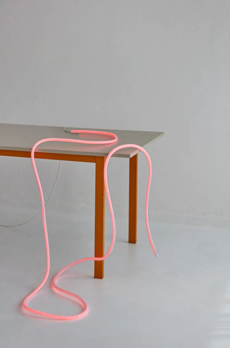 a table that has some kind of neon pink light on top of it, and an electric cord connected to the edge of the table