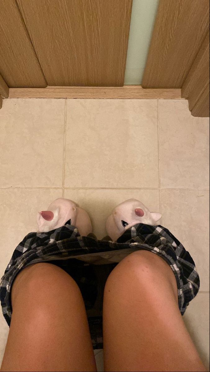 a woman's legs and shoes are seen from the top down on a bathroom floor