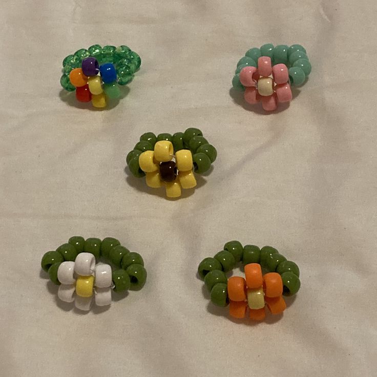 four different colored hair clips on a white tablecloth with beads in the shape of flowers