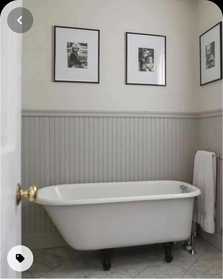 a white bath tub sitting next to two pictures on the wall