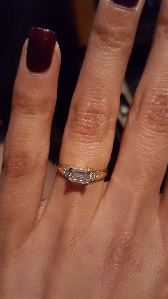 a close up of a person's hand with a ring on her finger and a red manicure