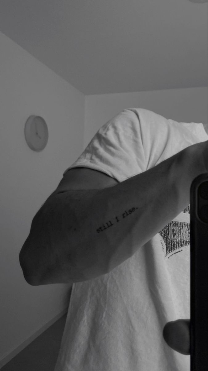 a man with a tattoo on his arm is taking a selfie in the mirror