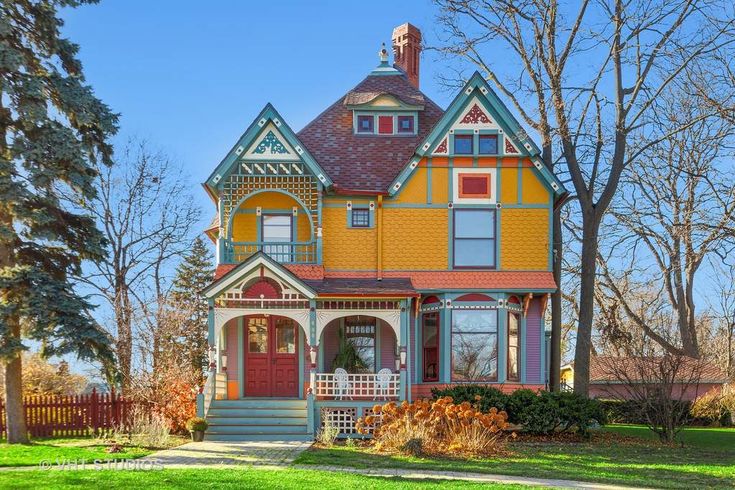 a multi - colored house with trees and grass in the front yard on a sunny day