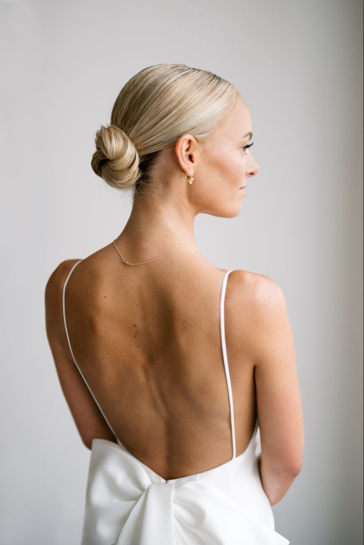 a woman wearing a white dress with a big bow on her back