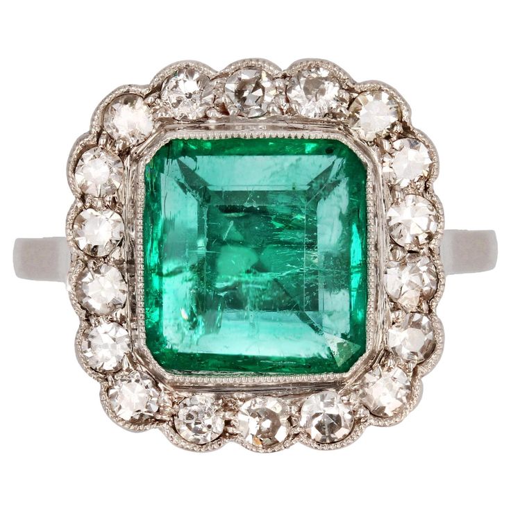 Ring in platinum. Sublime and feminine Art Deco ring, it is set with a rectangular- cut emerald in a surround of 8/8- cut diamonds bordered by a millegrain. The very flat setting presents an openwork basket. Weight of the emerald : 2.60 carats approximately. Emerald certified of Colombian origin. Total weight of the diamonds : 0.60 carats approximately. Height : 16.1 mm, width : 15.2 mm, thickness : 5.6 mm approximately, width of the ring at the base : 1.5 mm approximately. Total weight of the j Vintage Cluster Ring, Colored Stone Rings, Platinum Diamond Rings, Feminine Art, Jewelry Appraisal, Step Cut, Colombian Emeralds, Diamond Shop, Platinum Ring