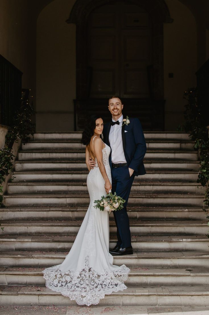 a bride and groom standing on the steps of an old building in front of some stairs