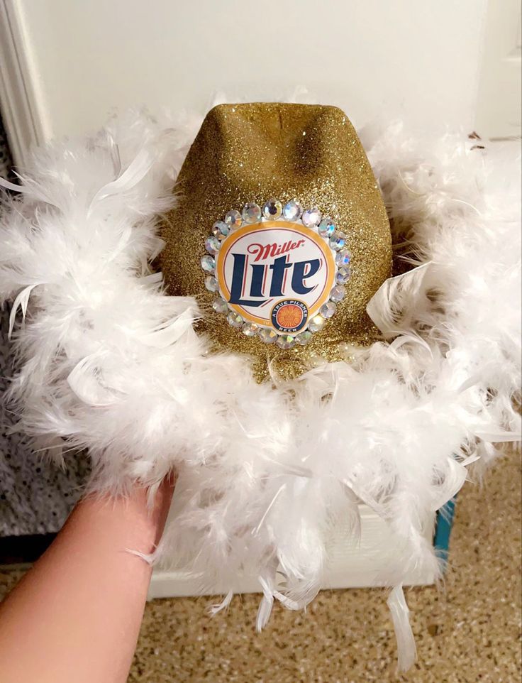 a hat with white feathers around it and a life logo on the front is in someone's hand