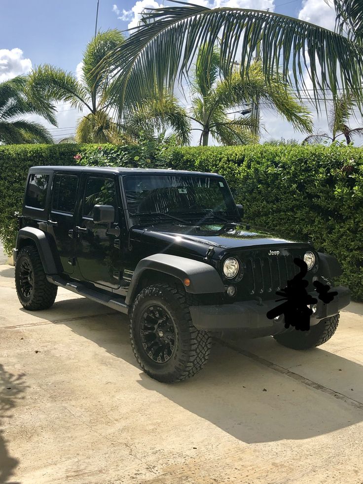 a black jeep parked in front of some bushes