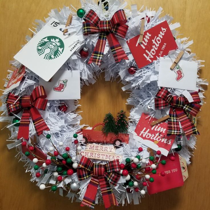 a starbucks christmas wreath with red and white ribbons, ornaments, and gift tags on it