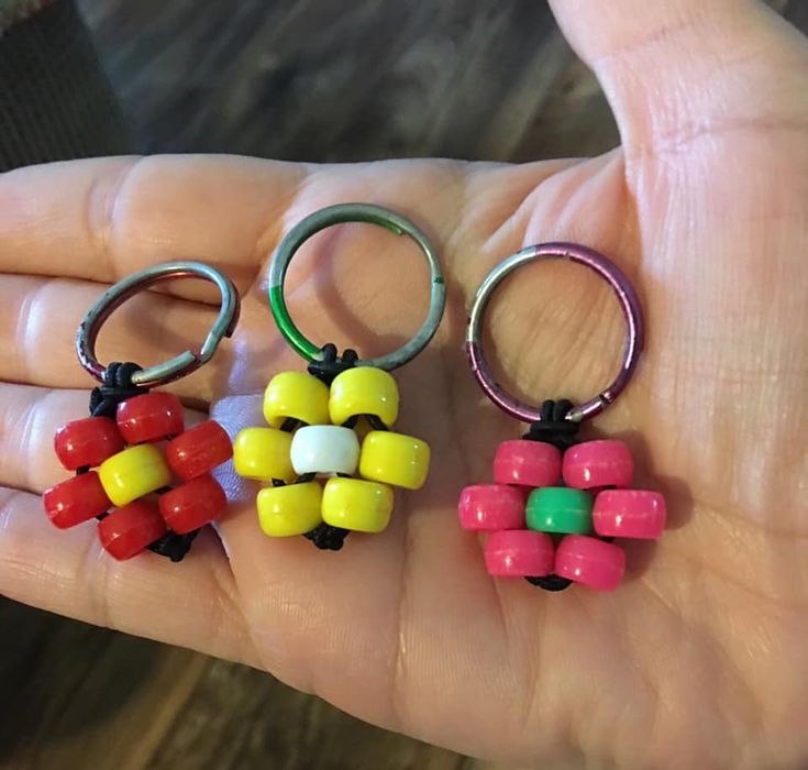 three different colored beads are in the palm of someone's hand with rings on them