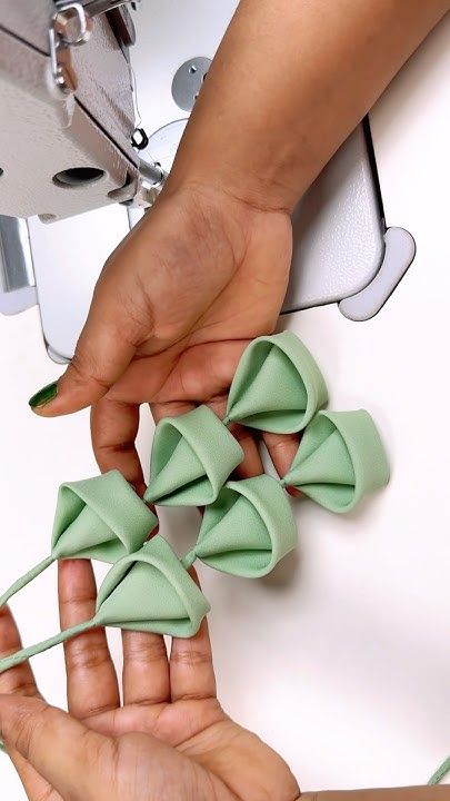 two hands are holding small green bows