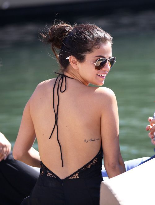 a woman in a black swimsuit with tattoos on her back