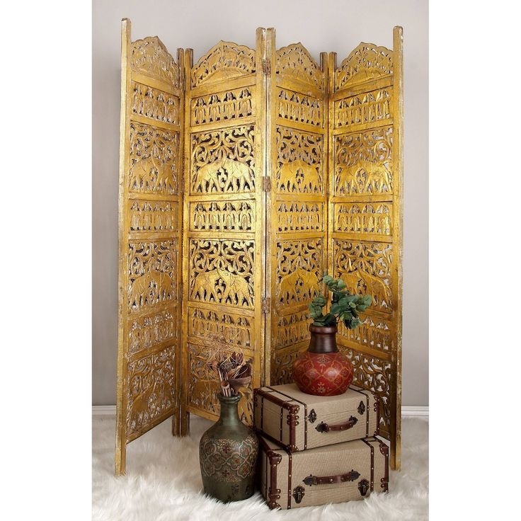 an ornate wooden room divider sitting on top of a white furnishing next to two vases