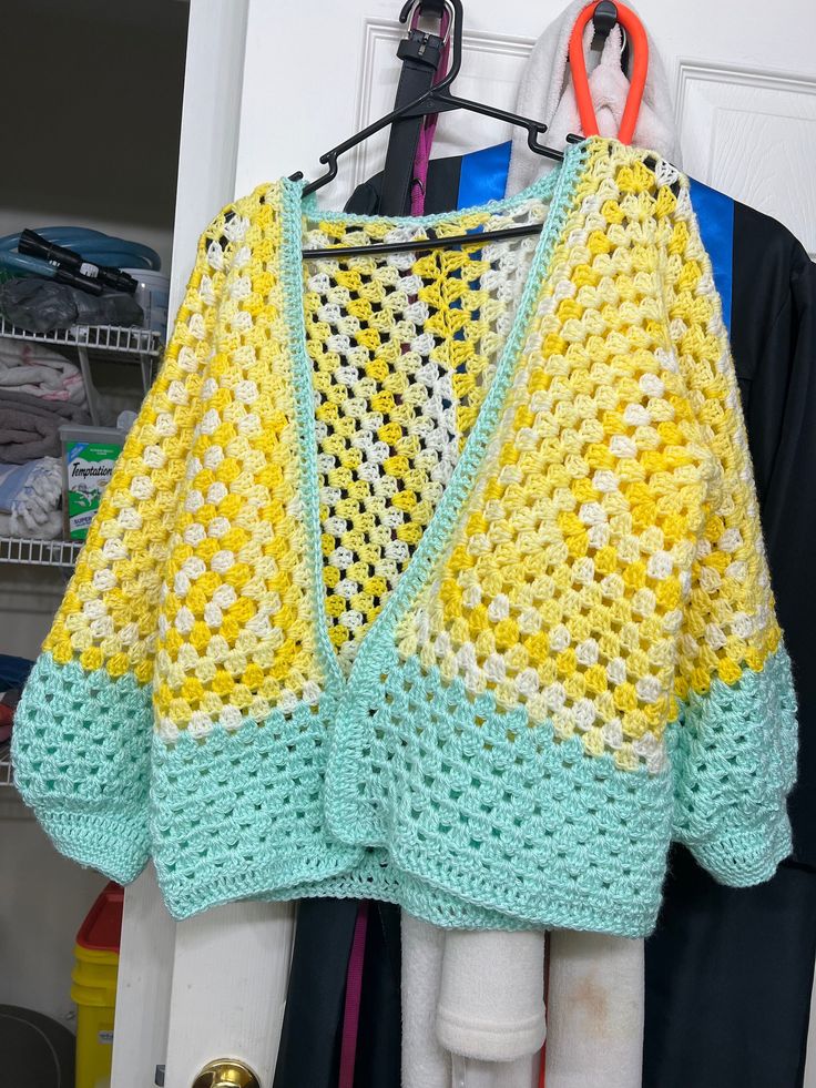 a crocheted sweater hanging on a clothes rack