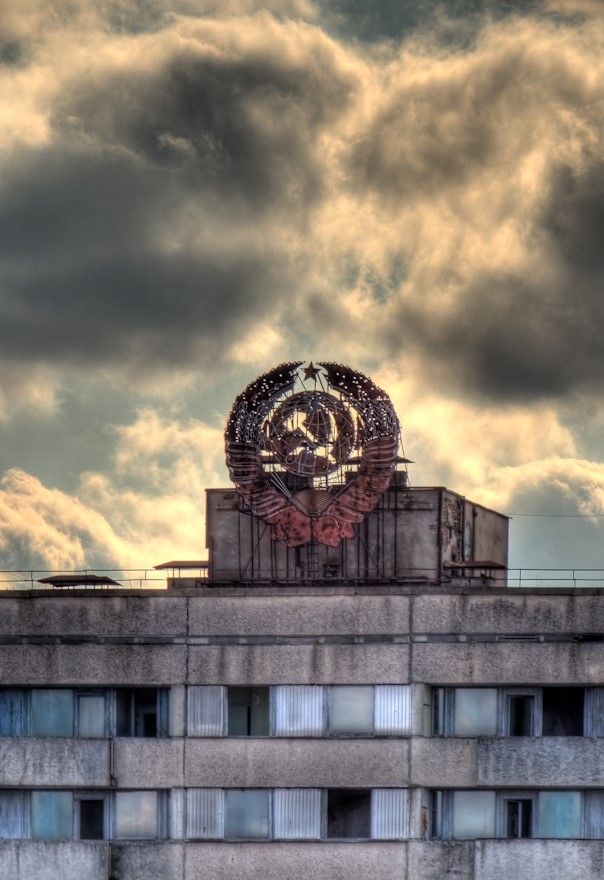 an old building with a clock on the top and cloudy sky in the back ground