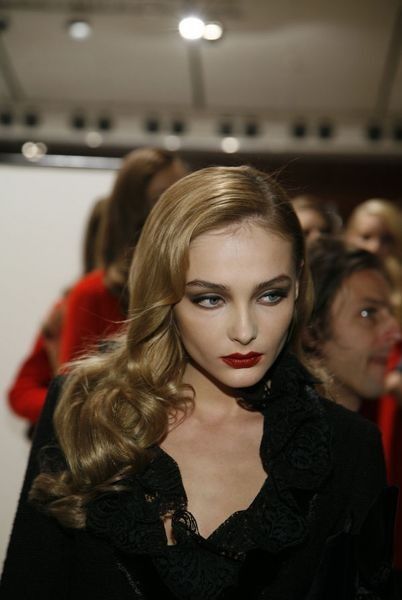 a woman with long blonde hair and red lipstick on the catwalk at a fashion show