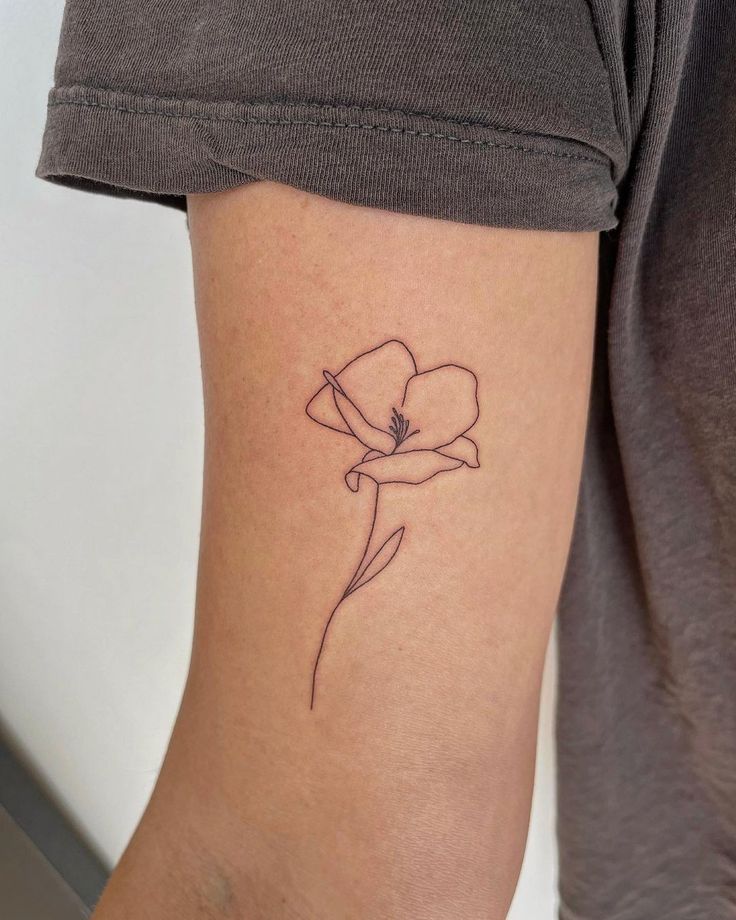 a small flower tattoo on the left arm